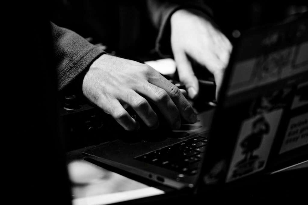 Black and white close-up of hands typing on a laptop keyboard, showcasing focus and concentration.